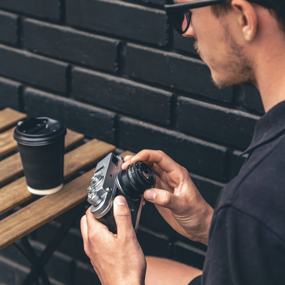 Vintage film camera and a glass of coffee on a wooden table.
